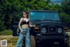 A woman standing in front of a black jeep.