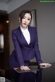 A woman in a purple suit sitting at a table.