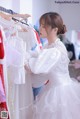 A woman in a white dress looking at a rack of dresses.