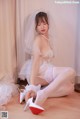 A woman in a wedding dress and high heels sitting on the floor.