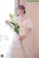 A woman in a wedding dress holding a bouquet of flowers.