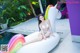 A woman in a white bikini sitting on an inflatable unicorn.