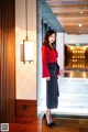 A woman in a red blouse and black skirt posing for a picture.