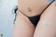 A woman in a black thong with a tattoo on her thigh.